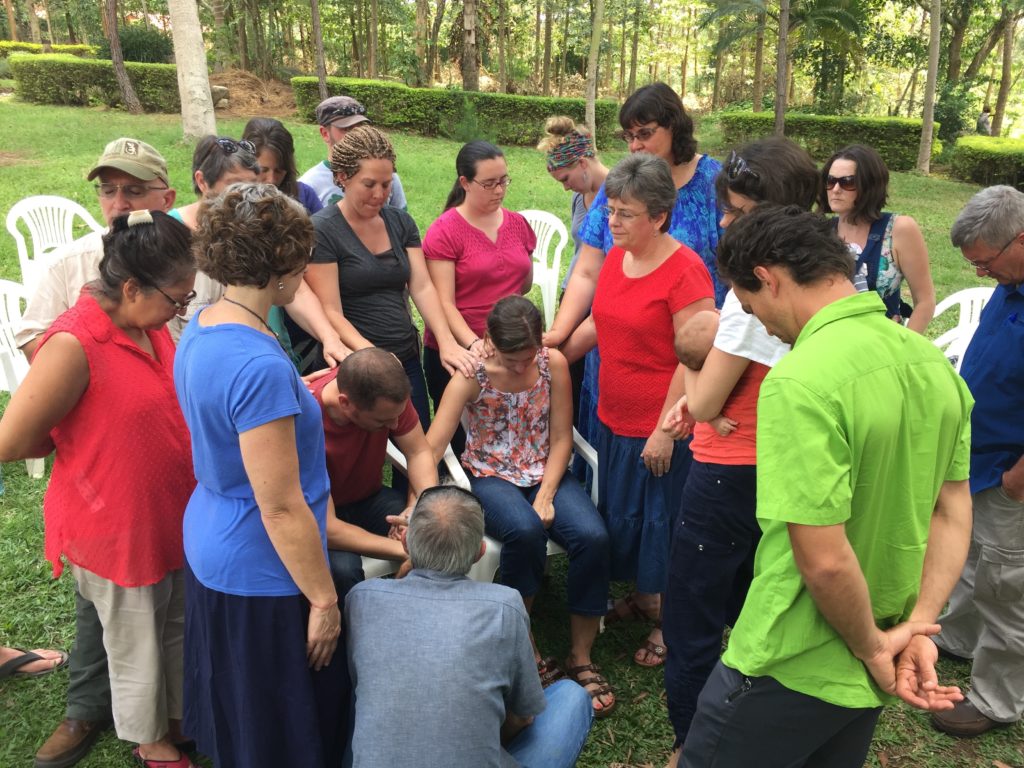 Foreign missionary staff praying over the McFarland's before they leave for furlough.